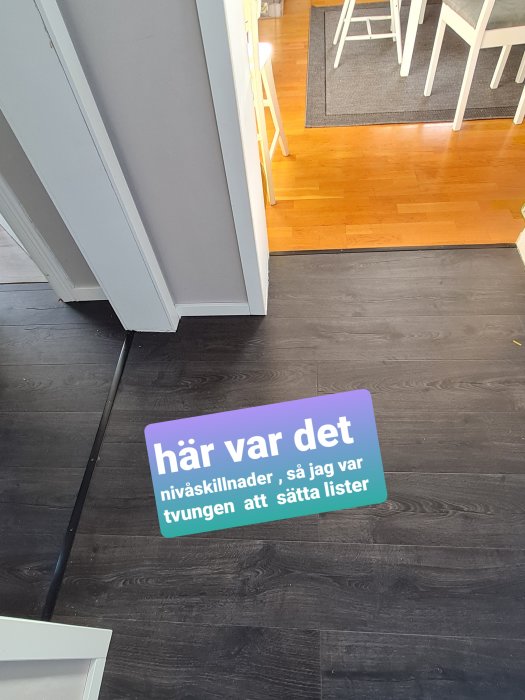 Nytt laminatgolv i grått möter äldre trägolv vid dörrtröskel med synlig höjdskillnad och text som beskriver situationen.