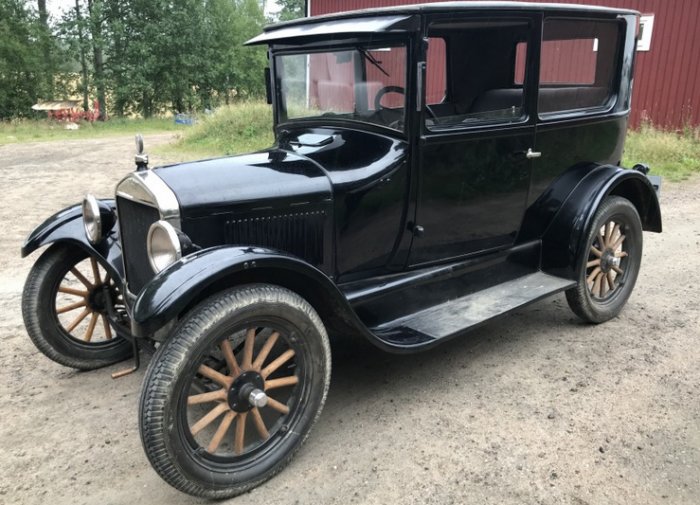 Renoverad svart T-Ford från 1920-talet parkerad på grusväg med röd lada i bakgrunden