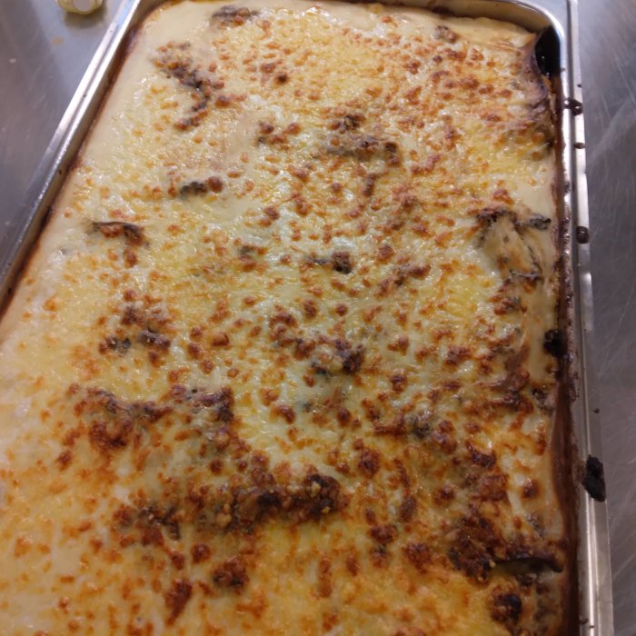 Nygräddad lasagne i form med smält ost och gyllenbrun yta.