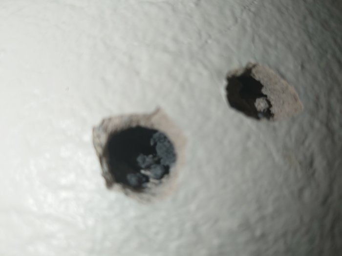 Två urgröpta hål i en vit vägg, som ser ut att ha bearbetats över tid.