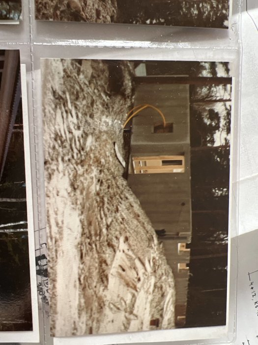 Svartvit bild av byggarbetsplats med gjuten bottenplatta och uppsatta ytterväggar inomhus.