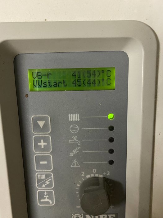 Närbild på kontrollpanelen av en Nibe bergvärmepump med inställningar och grönt lysande indikatorljus.