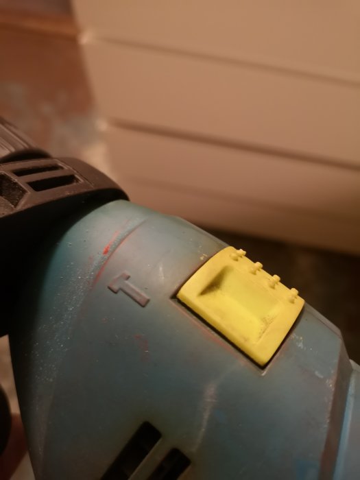 Närbild av en använd blå borrskruvdragare med en gul slagfunktionsväljare.