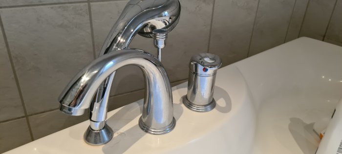 Kromad badkarsblandare med termostatinsats och justerskruv, monterad på handfat.
