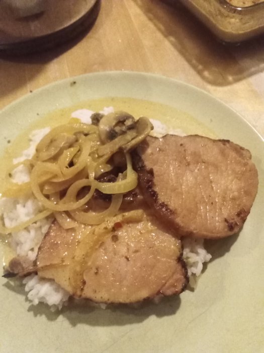 Karibisk kassler med ris, lök, champinjoner, ananas och kryddig sås på en tallrik.
