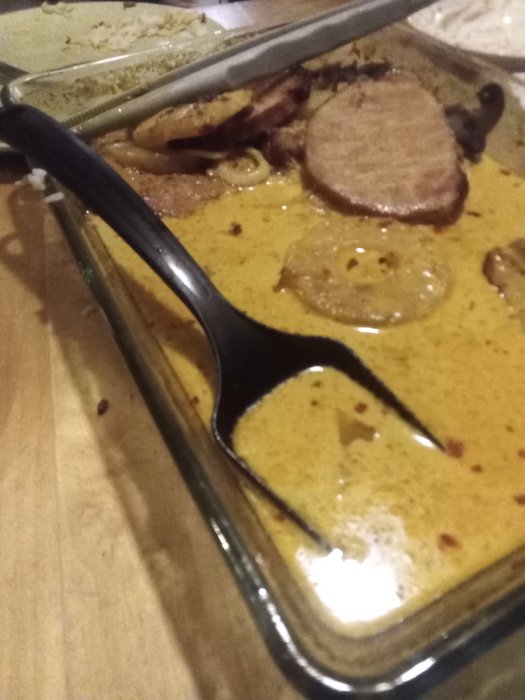 Karibisk kassler med ananas, lök och champinjoner i en ugnsform med kokosmjölksås och kryddor.