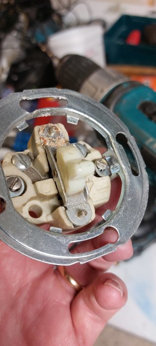 Specialskruv hålls upp framför en verktygssamling, synlig invändig gänga och grå metallfärg.