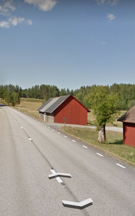 Lantlig väg i Dalsland före installation av räcke, med röda lador och grönska.