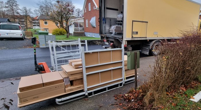 Första leveransen av köksskåp vid huset med paket och pallar framför en leveransbil.