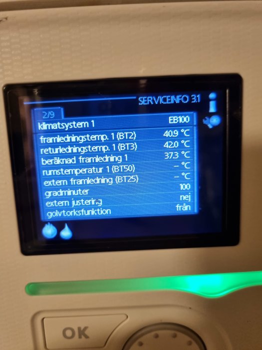 Digital display på en värmeanläggning som visar temperaturinformation och systeminställningar.