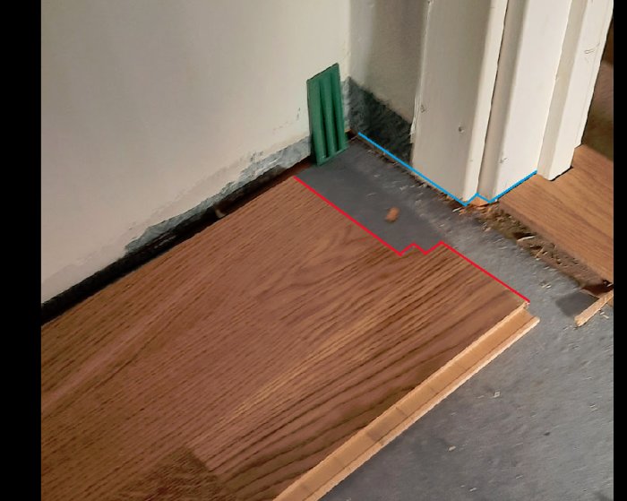Golvläggning vid dörröppning med bräda sågad för att passa under dörrtröskel och karm.