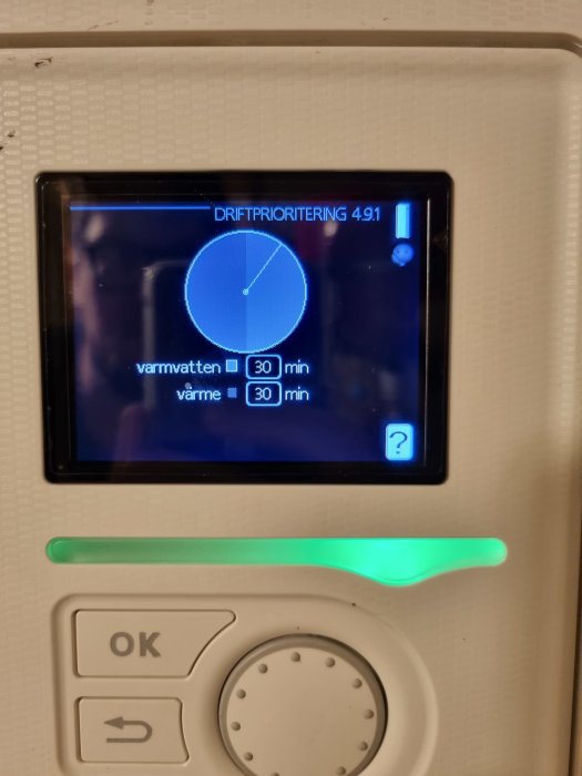 Digital display visar driftsprioritering av varmvatten och värme med tidsangivelser, och en grön lysstav.