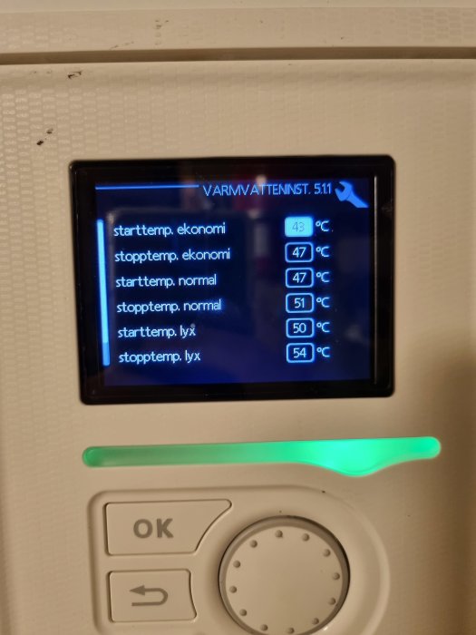 Digital display på en värmepanna visar temperaturinställningar för varmvatten i olika lägen.