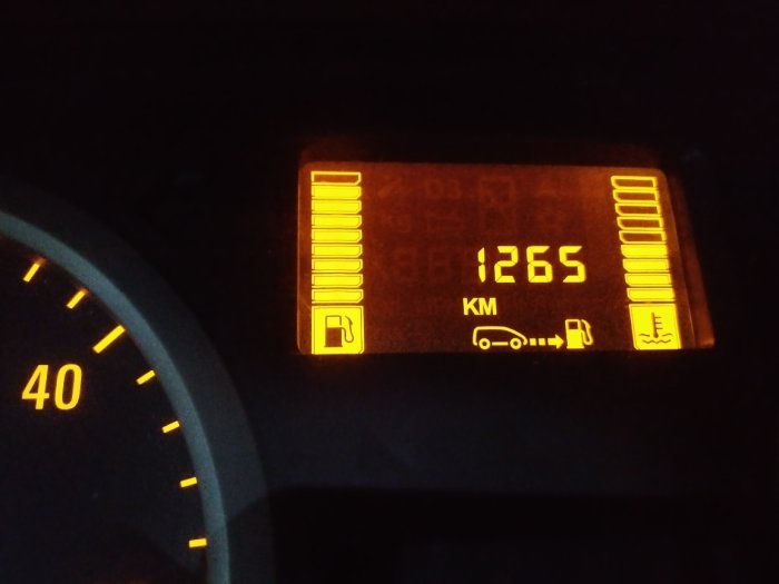 Bilinstrumentpanel som visar bränslemätare och återstående körsträcka på 1265 km.