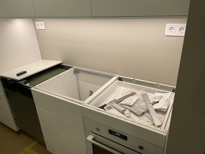 Köksskåpsstomme utan bänkskiva med öppen låda och väggkontakter.