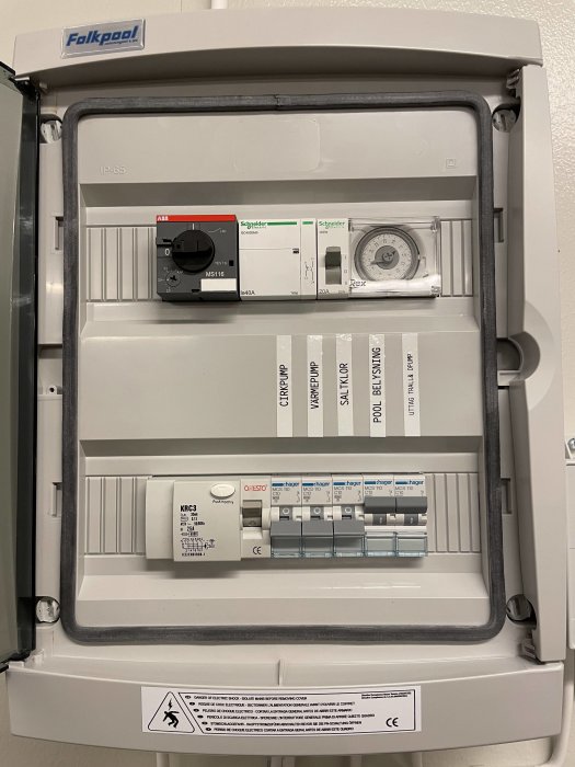 Elskåp med märkning för poolens elektriska komponenter: pump, belysning och saltklorinator.