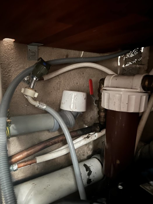 Rörinstallation i källare med läckande rör och vattenfiltreringssystem.