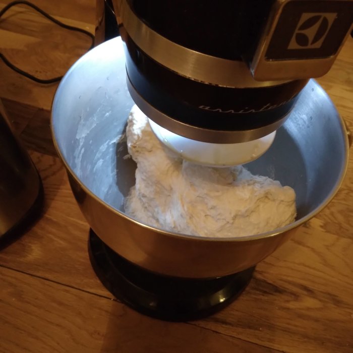 Deg som blandas i en köksmaskin på ett nylagt trägolv.