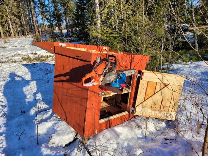 Stor verktygslåda med lastarfästen i snöig terräng, innehåller motorsågar och utrustning.