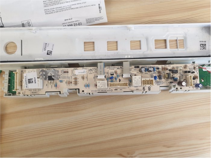 Demontage av tvättmaskinens kretskort med synliga kondensatorer, motstånd och markerade testpunkter.