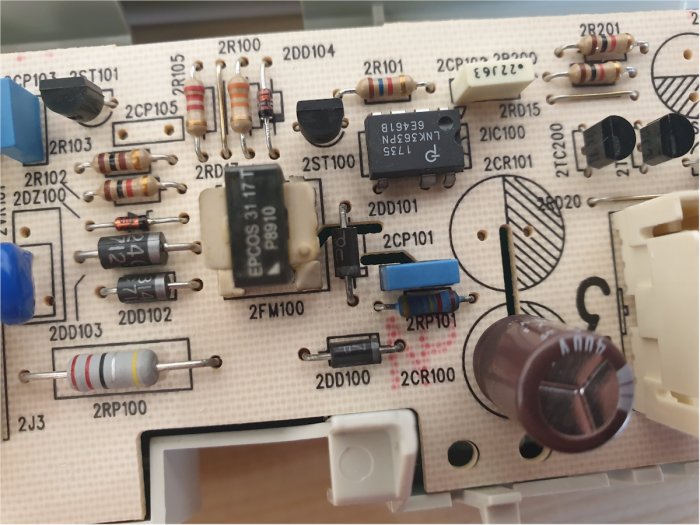 Tvättmaskins kretskort med komponenter som resistorer, kondensatorer och dioder, några ser svedda ut.