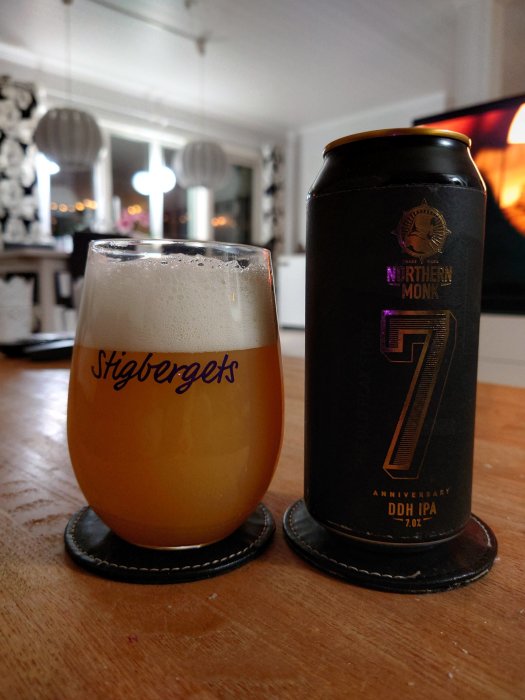 Ett glas DIPA-öl från Northern Monk på ett underlägg bredvid burken på ett träbord inomhus.