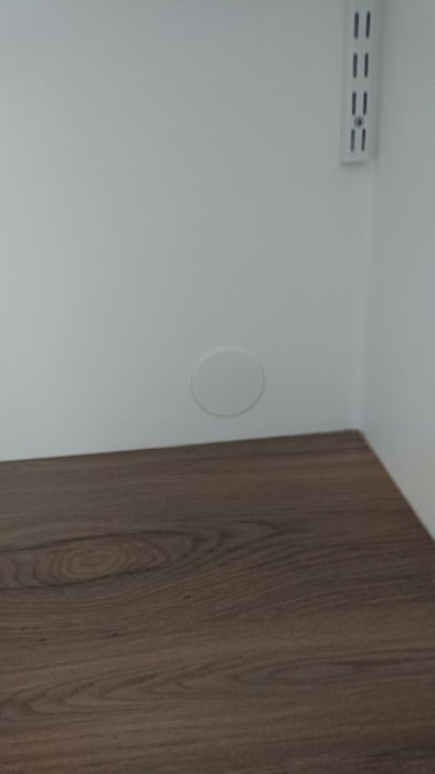 Vägg med doslock där illaluktande doft upptäckts, nära en brun tröskel och vit strömbrytare.