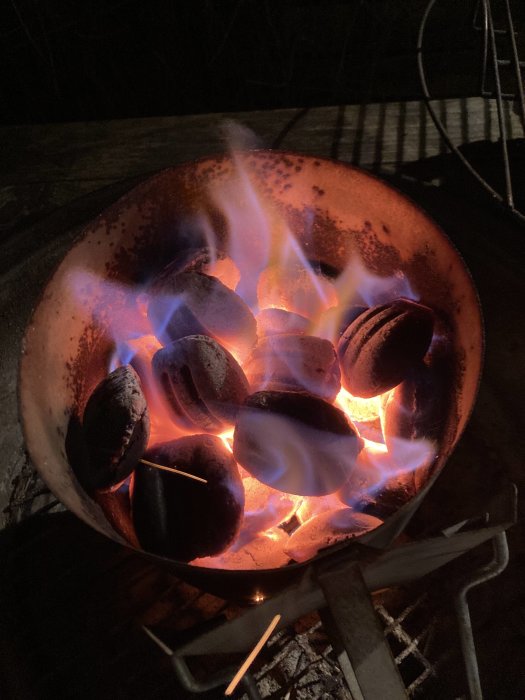 Glödande grillkol i en grillpanna redo för grillning av mat utomhus på kvällen.