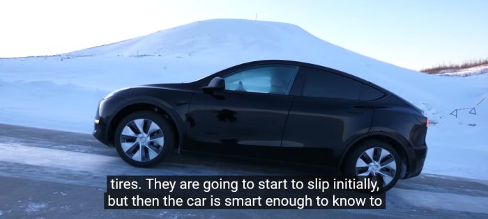 Tesla Model Y startar på en isig uppförsbacke med en snötäckt landskap i bakgrunden.