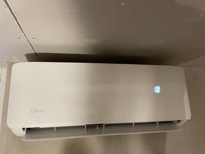 Värmepump installerad under ofärdig gipstak med synliga skruvar och en glipa behövande spackling.
