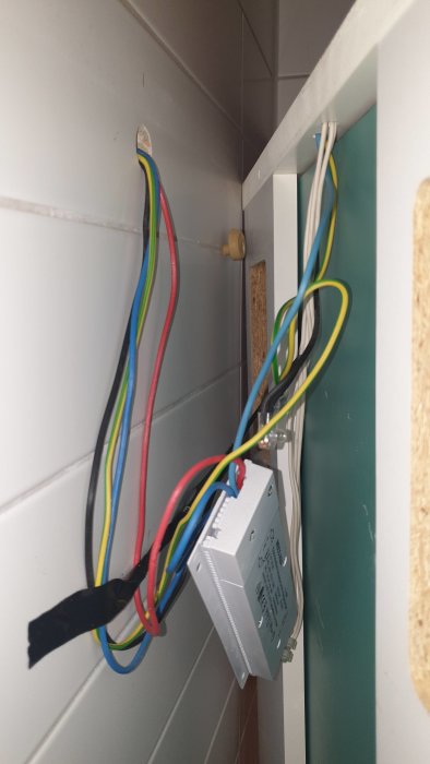 Elektriska installationer med synliga kablar och ett eluttag i ett öppet utrymme.