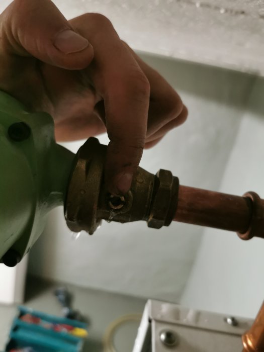 Hand justerar ventil på rör där det läcker vatten, behov av identifiering och reparation.