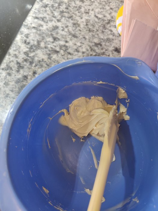 Blå skål med ankfettlever som blandas, synlig spatel och köksbänk i bakgrunden.