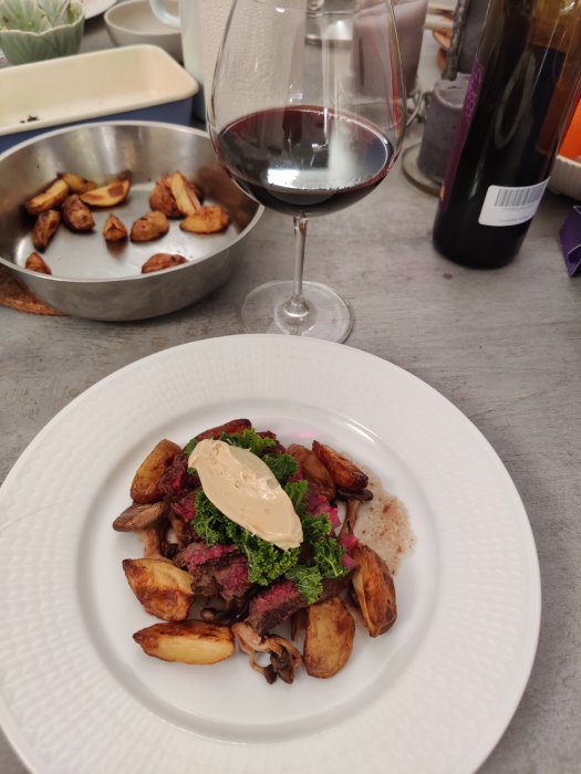 Ryggbiff medium rare med ankleversmör på toppen, omgiven av stekta ostronskivlingar och potatisklyftor, bredvid ett glas rödvin.