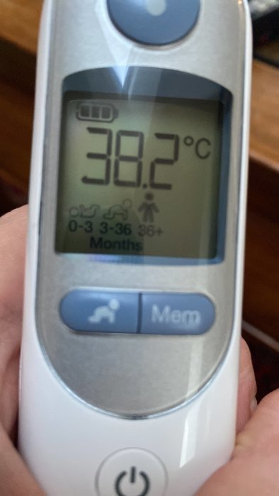 Digital termometer visar en febertemperatur på 38.2°C.