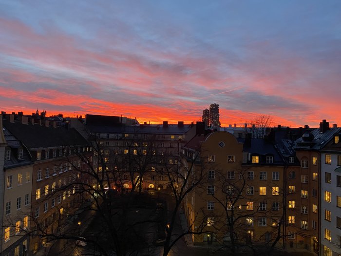 Solnedgång över stadssilhuetten med färgstark himmel och byggnadernas konturer.