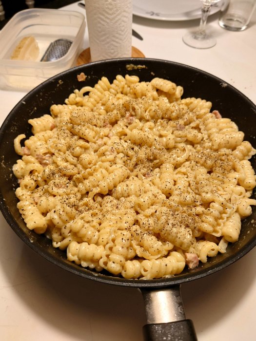 En stekpanna med färdiglagad Carbonara toppad med svartpeppar, redo för middag.