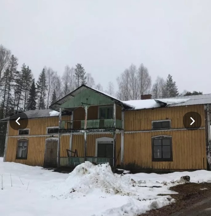 En tvåvånings trähus med snö på taket och marken som behöver rivas för att återanvända material.