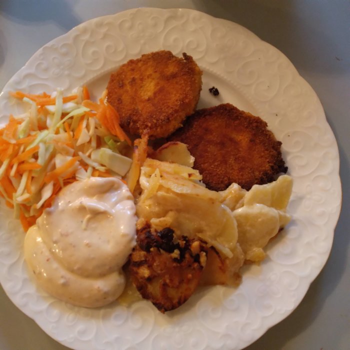 Morotsbiffar med parmesan, potatisgratäng och sweetchilimajonnäs på en vit tallrik.