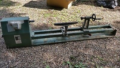 Gammal grön Holz-drehbank G 1000 träsvarv på marken omgiven av grus och gräs.
