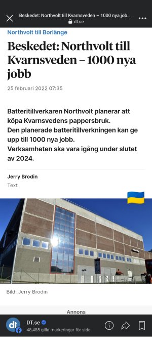 Industribyggnad med stora fönster och en ukrainsk flagga hissad på taket mot en klarblå himmel.