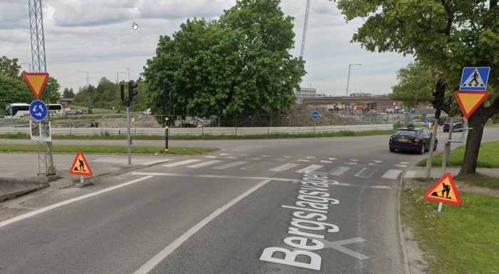 Gatuvy av Bergslagsplan med vägskyltar, trafikljus och rondell i bakgrunden.
