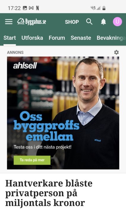 Leende man i Ahlsell-arbetsklädsel framför hyllor med byggmaterial, reklam för byggproffs.