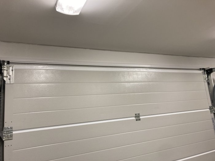 Garageport med tre inbyggda spottar i taket och kablar dolt installerade längs med porten.