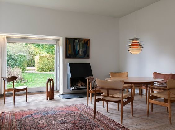40-talsstil inredd vardagsrum med klassiska möbler, öppen spis och utsikt mot trädgården genom en glasdörr.