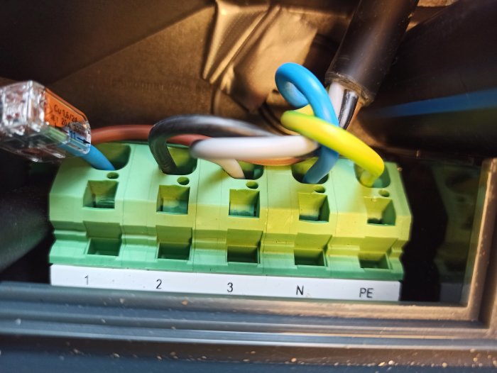 Elektriska kablar anslutna till en grön anslutningsplint, märkt med "16/24A" och "450/750V".
