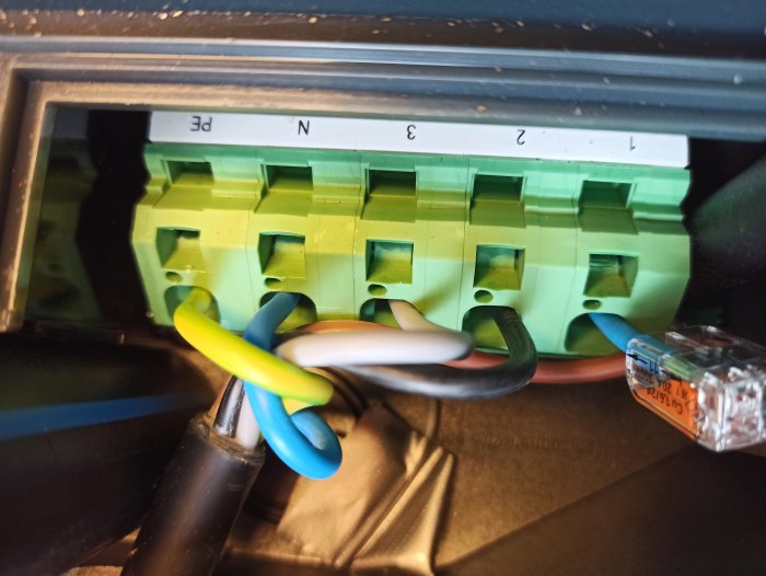Mångtrådig kopparledning ansluten till en grön elektrisk kopplingsplint.