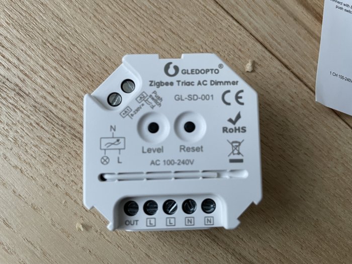 En Zigbee Triac AC Dimmer för belysning med märkningen N, L och OUT synlig på bordet.