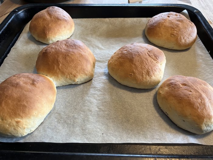 Färska nybakade semlor på en ugnsplåt, redo för fyllning.