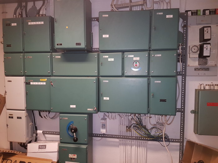 Elektriska kapslade elcentraler och säkringsskåp monterade på vägg i ett tekniskt utrymme.